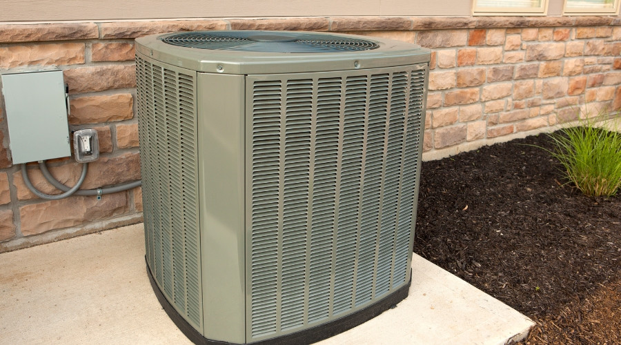 Air conditioning unit installed outside a home, highlighting the importance of maintenance for energy efficiency and cooling cost reduction.