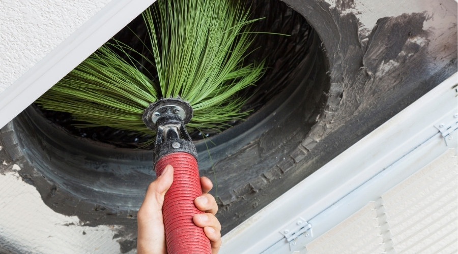 Air duct cleaning tool with bristles removing dust and debris from ductwork, highlighting professional cleaning services for improved indoor air quality.